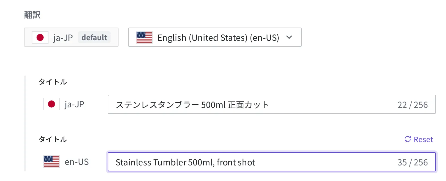 Media 編集フォームの翻訳セクション。ja-JP のタイトル「ステンレスタンブラー 500ml 正面カット」と en-US のタイトル「Stainless Tumbler 500ml, front shot」が並んで入力された状態